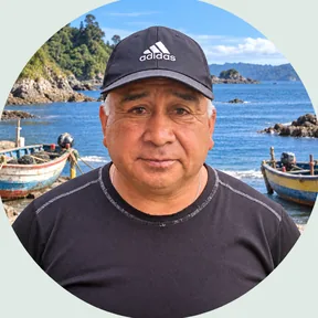 Helio Quinan en la caleta de Bonifacio, con botes de pescadores y el mar de fondo